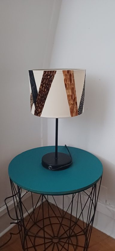 Lampe à abat-jour clair avec motifs géométriques en marqueterie de plumes naturelle